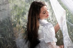 Portrait of model with long hair in white dress in a grass