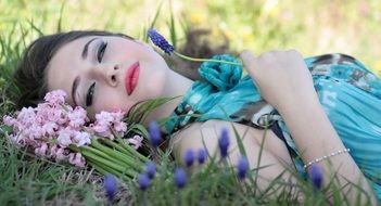 beautiful girl lies among flowers on the grass close up
