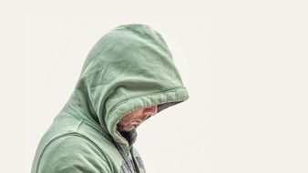 man with a beard in a green hood of sweatshirt