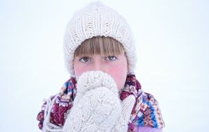 Girl in a knitted cap and mittens in winter