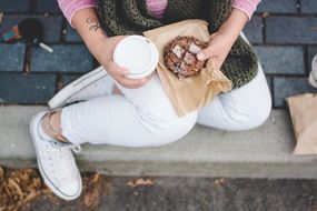 cup with coffee and a bun in hands