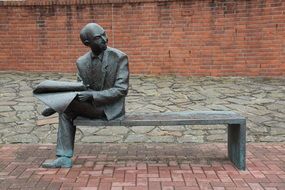 sculpture of a man on a bench with a newspaper