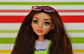 doll with sunglasses on her head on a background of colored bands