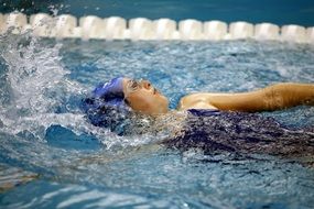 woman in blue cap swims in the pool