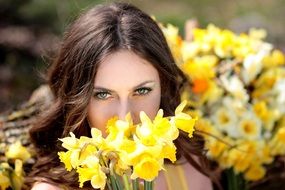 woman smelling yellow daffodils