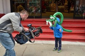 Child boy wearing Crocodile form Balloon posing in front of Camera