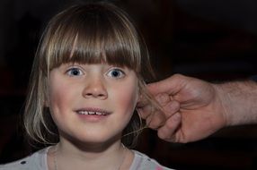 male hand holding child girl by the ear