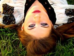 girl with bright makeup lies on the grass