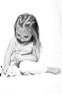 little girl is sitting with her toy