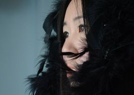 Asian girl in a black scarf with feathers