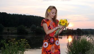 beautiful girl with sunflowers near the water