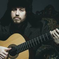 musician wearing a fur hat with a guitar