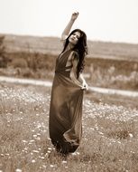 Monochrome photo of girl in a long dress among nature