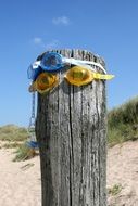 pacifier and swimming glasses on wooden pile on beach