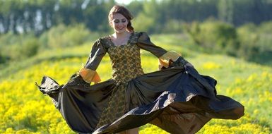 girl running in the princess dress in a meadow with yellow flowers