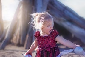 little girl in a burgundy dress on the beach