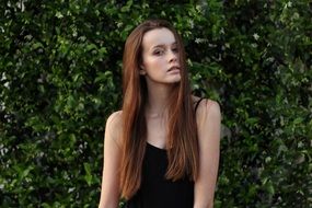 beautiful girl by the green hedge