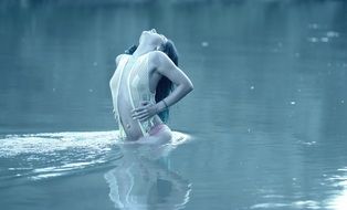 Girl in a transparent swimsuit posing in the water