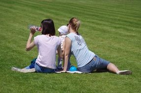 girls with a child have a rest on a green lawn