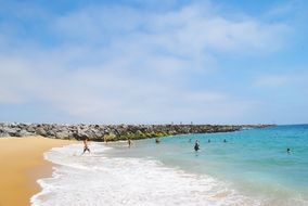 people in waves on the beach on a sunny day