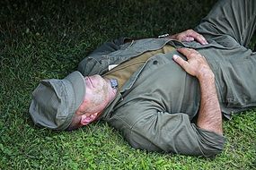 soldier in uniform is resting on the grass