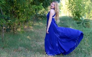 attractive woman in blue evening dress among the plants