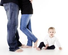 the child sits on the floor near the feet of the parents