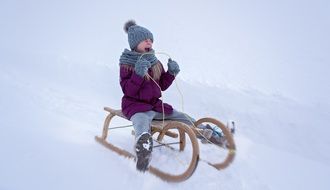 girl in a purple jacket on a sleigh