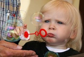 baby girl blowing soap bubbles