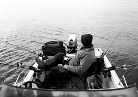 Man Fishing with rods in Boat, black and white image