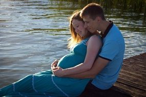 married couple sitting on a stone near the water