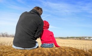 dad and son are sitting on straw
