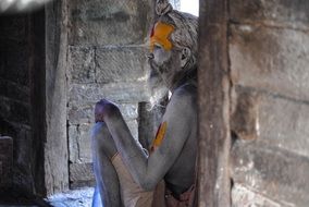 Indian man sitting near a wall in a temple