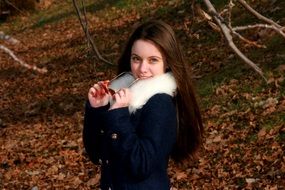 girl in a jacket with white fur on a background of the autumn landscape