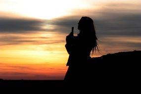 silhouette of a woman with a gun at sunset