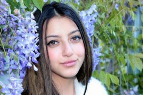 pretty girl with brown eyes at blue flowers