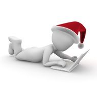 Santa Claus lying on the floor with a laptop