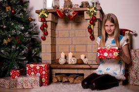 Christmas girl by the fireplace with gifts