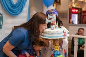 mother with baby tries birthday cake at the birthday party