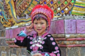 girl in traditional Asian costume at the temple wall with beautiful and colorful ornaments