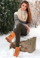beautiful girl sitting on a stone among the snowy landscape