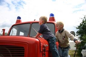 two Child boys at red fire car outdoor