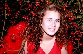 girl in a red angel costume among red berries