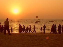 orange sky over the silhouettes of people on the beach in india