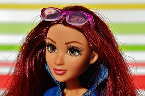 doll with sunglasses on her head in a denim jacket