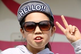 portrait of a child with glasses and cap with the inscription hello