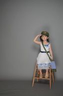 girl sitting on a chair near the wall in a military cap