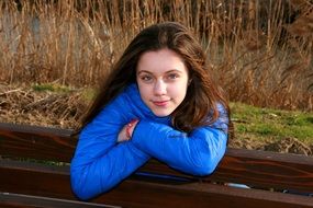 beautiful girl in a blue jacket on a bench