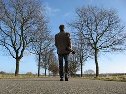 Person is walking on the road with the trees