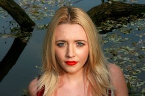 blonde with red lips near the water